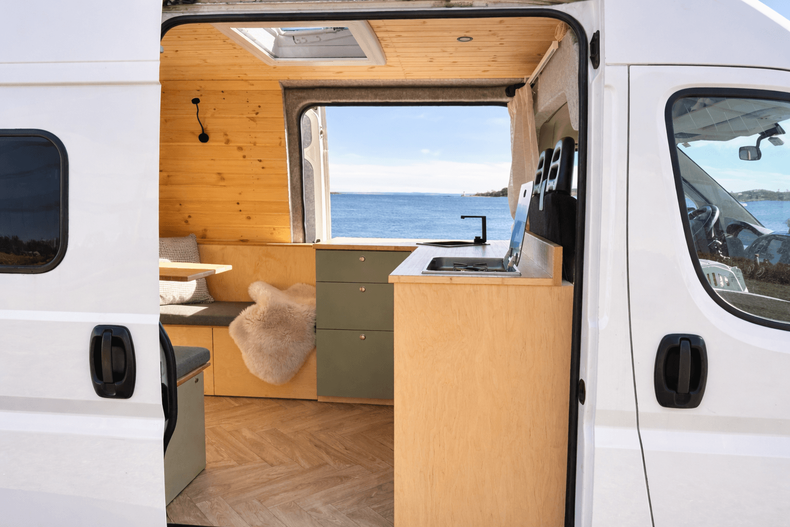 Campervan seen from the rear with open sliding door and sea view